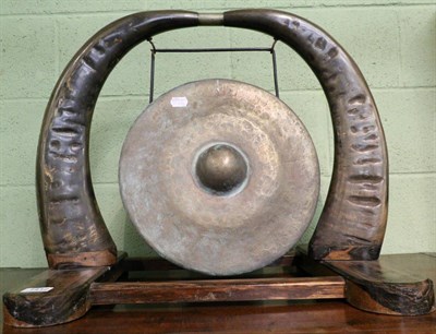 Lot 1412 - An early 20th century dinner gong with water buffalo horn supports on an ebony base