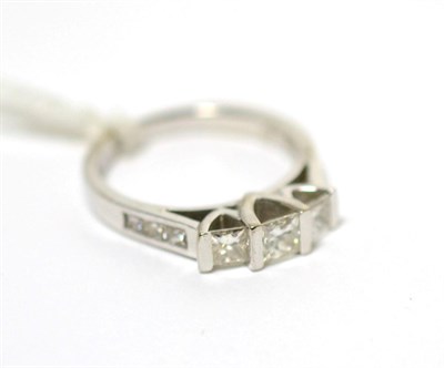 Lot 236 - A three stone princess cut diamond ring with diamond set shoulders (with original receipt)