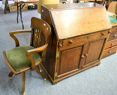 Lot 1085 - An oak writing bureau and an oak desk chair on castors