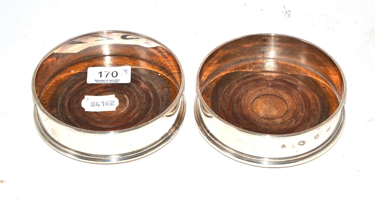 Lot 170 - A pair of silver wine coasters, YP, London 1975, with turned wooden bases, 12.5cm in diameter (2)