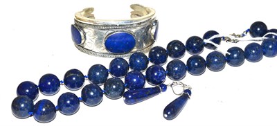 Lot 210 - A lapis lazuli bead necklace, a pair of lapis lazuli drop earrings and a lapis lazuli cuff bangle