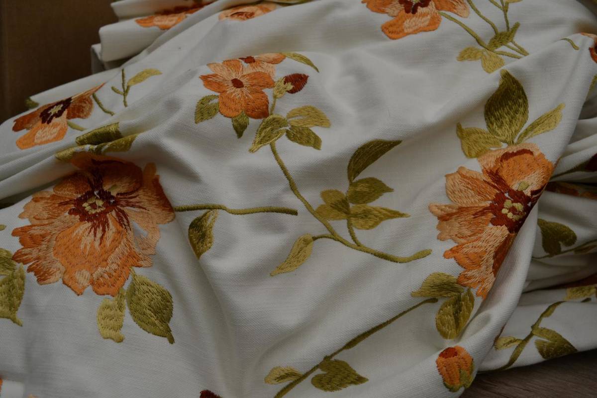 Lot 1004 - A pair of peach floral embroidered curtains on white linen ground