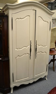 Lot 1088 - A cream painted armoire of recent date with moulded canopy top above panel doors enclosing...