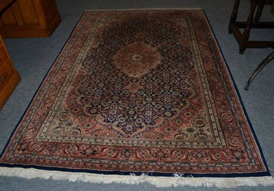 Lot 1118 - An Indian rug, the indigo Kerati field centred by a terracotta medallions, central by samovar motif