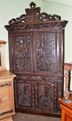 Lot 1192 - An early 20th century ornately carved oak corner cupboard with shield and bishop's miter crest...