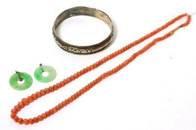 Lot 102 - A Chinese bangle, a graduated coral bead necklace with a barrel clasp stamped '9C', length 56cm and