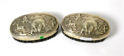 Lot 44 - A pair of Burmese white metal backed gentleman's brushes decorated in repousse with hunting scenes