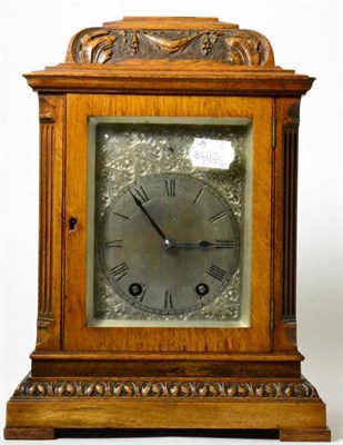 Lot 56 - An oak striking carved mantel clock, circa 1910, inverted pediment, side sound frets, silvered dial