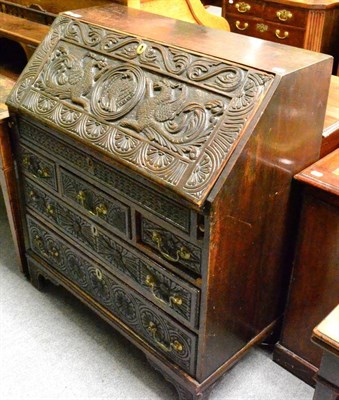 Lot 1300 - A George III and later carved oak bureau