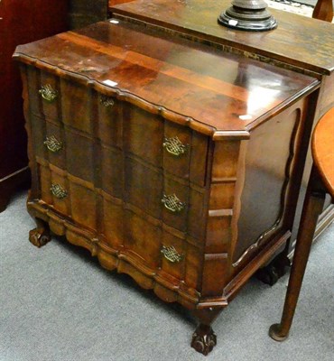 Lot 1310 - A small stinkwood chest of drawers, the front of serpentine form, raised on four ball and claw feet