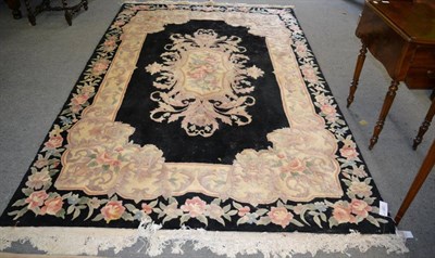 Lot 1344 - A Savonerie design carpet, the jet black field centred by a floral oval medallion framed by...