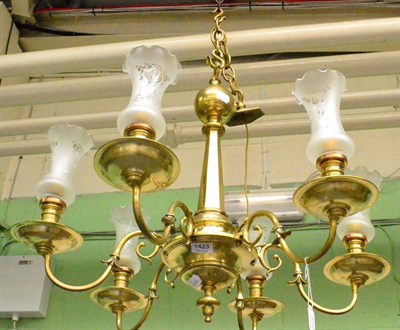 Lot 1423 - A brass six branch chandelier with glass shades