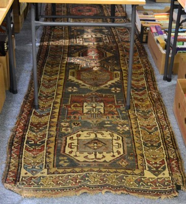 Lot 1105 - North West Persian runner, the field with a column of medallions enclosed by ivory borders,...