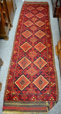 Lot 1114 - Narrow Balouch piled and flatwoven runner, the diamond lattice field enclosed by narrow...