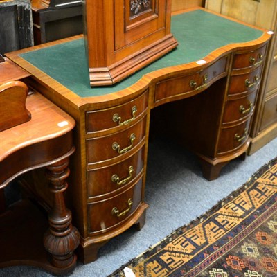 Lot 1135 - A Georgian style mahogany serpentine kneehole desk, leather inset, arrangement of nine drawers,...