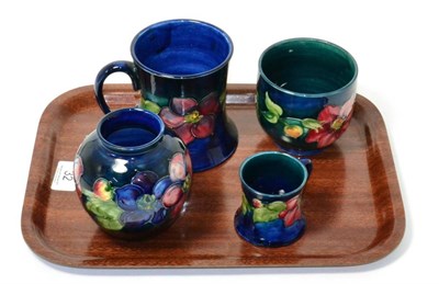 Lot 32 - Four pieces of Walter Moorcroft pottery, in the Clematis pattern including two mugs (one a.f.)...