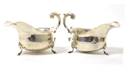 Lot 85 - A pair of silver sauce boats with c scroll handles and each raised on three feet