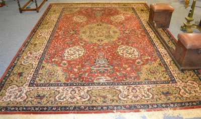 Lot 1123 - A machine made carpet of Indian design, the brick red field of birds animals and vines around a...