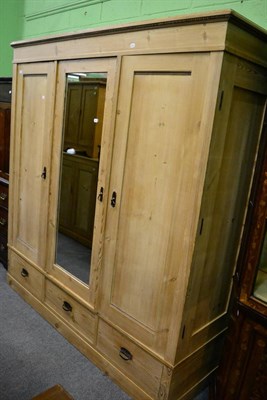 Lot 1237 - A pine mirror fronted triple wardrobe