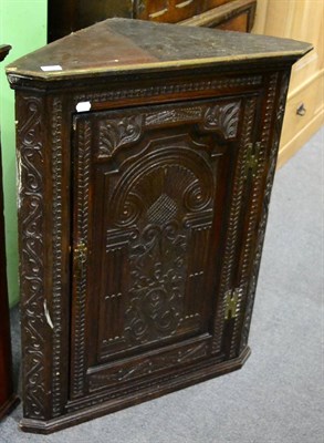 Lot 1239 - A 19th century carved oak hanging corner cupboard