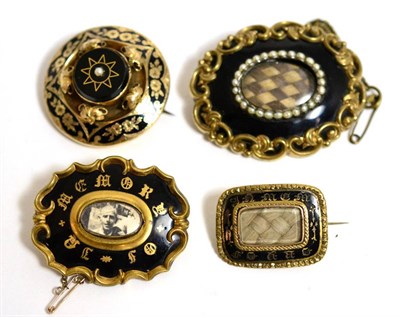 Lot 45 - A group of four Victorian enamel and yellow metal mounted mourning brooches