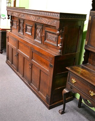 Lot 1321 - A Queen Anne oak court cupboard, the integral cornice with carved frieze of floral lunettes...