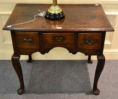 Lot 1342 - An 18th century oak lowboy, the moulded top above three drawers with later brass handles above...