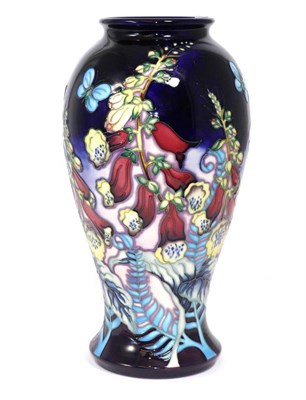 Lot 349 - A modern Moorcroft pottery vase, decorated with foxgloves and butterflies on a blue ground,...