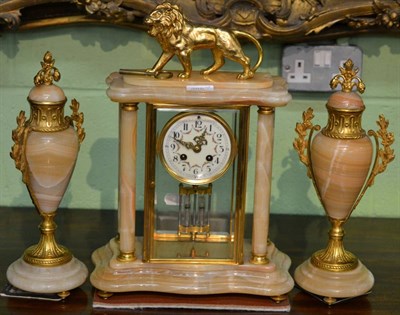 Lot 385 - A gilt metal mounted striking clock garniture surmounted by a lion