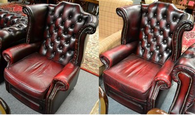 Lot 1318 - A pair of George III style ox blood leather wingback armchairs