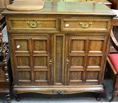 Lot 1382 - A reproduction oak sideboard of small proportions, with two panel cupboards and two narrow drawers