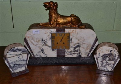 Lot 389 - An Art Deco marble clock garniture, the clock surmounted by a gilt metal recumbent hound (3)