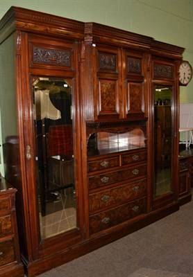 Lot 654 - A three piece walnut veneered and mahogany bedroom suite comprising mirrored wardrobe, mirrored...