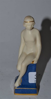 Lot 316 - A Royal Worcester figure of a nude holding her shoe, seated on a blue glazed plinth, with puce...