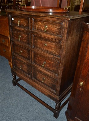 Lot 1098 - A 1920's oak chest of drawers, with four graduated drawers, on turned legs joined by...