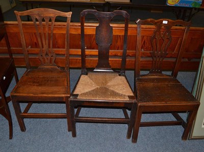 Lot 1137 - Two George III oak plank seated chairs with yolk crest rails and a Queen Anne rush seated oak chair