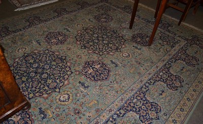 Lot 1335 - A machine made carpet of Oriental design, the pale olive green field with two medallions surrounded