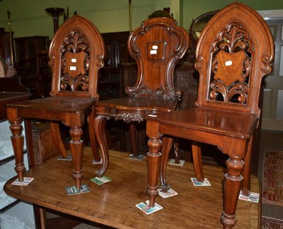 Lot 1353 - A pair of 19th century mahogany plank seated hall chairs in the Gothic style, together with a...