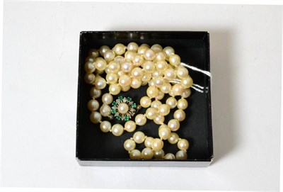 Lot 68 - A cultured pearl necklace with an emerald set clasp (one stone missing)