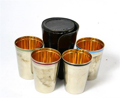 Lot 131 - A set of four white metal and enamel stacking hunting cups, with gilt interiors, in a hide case