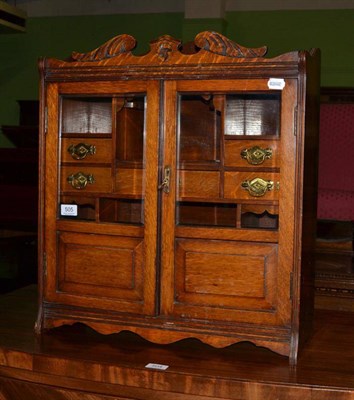 Lot 505 - An early 20th century oak smokers cabinet with glazed panelled doors opening to reveal an...