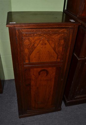 Lot 536 - An Arts & Crafts oak cupboard with pokerwork door, depicting Saint Frideswyde (Frideswide)...