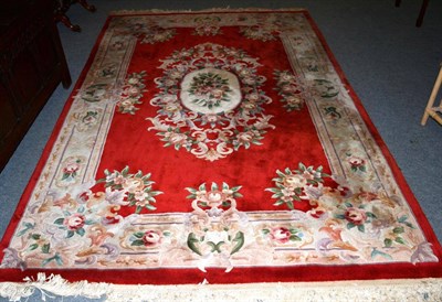 Lot 546 - A Chinese carved carpet of Savonnerie design, the red field centred by a floral panel framed by...