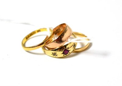 Lot 49 - A 22ct gold band ring, a 9ct gold band ring, a band ring and a 9ct gold ruby and diamond three...