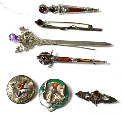 Lot 292 - A Scottish hardstone kilt pin, two others, two thistle brooches, a golf brooch and another