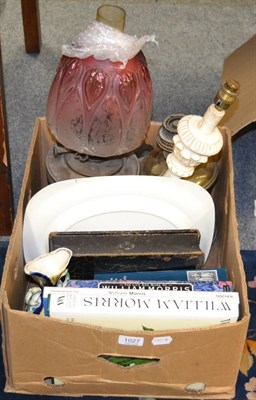 Lot 1027 - A brass oil lamp with cranberry shade, a further oil lamp, a meat plate, books relating to...