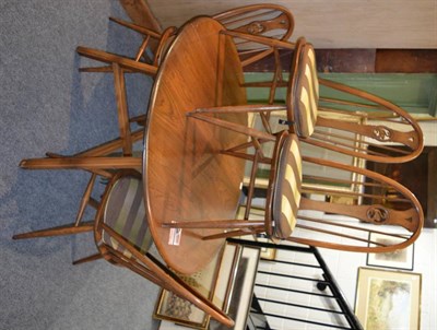 Lot 1112 - An Ercol elm drop leaf dining table together with four matching chairs