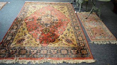 Lot 1143 - A machine made carpet of Oriental design, the coral field of vines centred by a pole medallion...