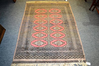 Lot 1145 - A Pakistani Bukhara rug, Lahore, the terracotta field with two columns of diamond medallions...