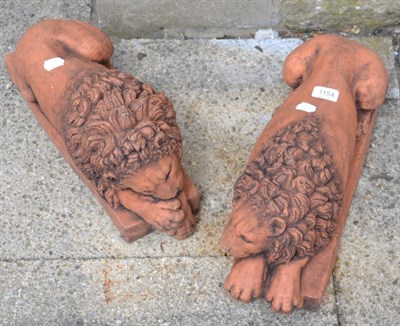 Lot 1154 - A pair of terracotta recumbent lions, 45cm long, 21cm high